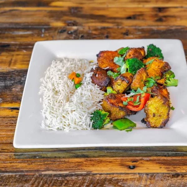 Indian dish with basmati rice, spiced chicken or paneer, broccoli, and bell peppers on a white plate.